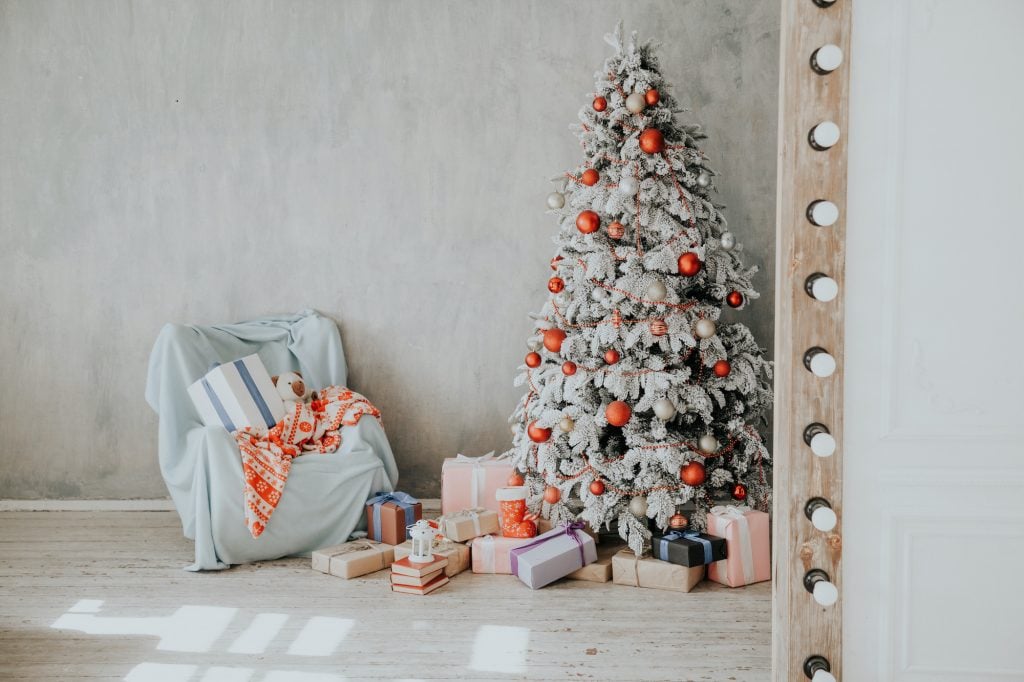 Flocked tree with snow and red baubles and presents under the tree.